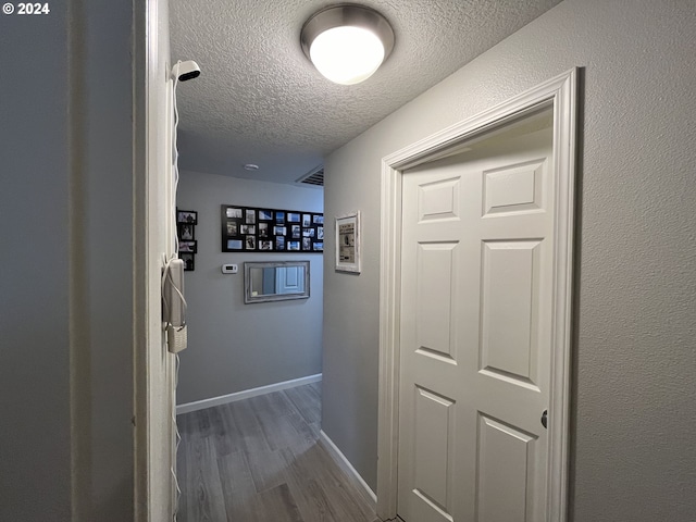 hall with a textured ceiling and hardwood / wood-style floors