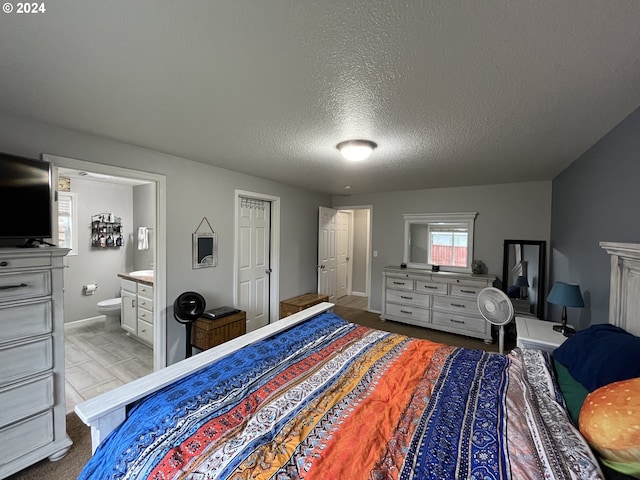 bedroom with a textured ceiling, connected bathroom, and light hardwood / wood-style flooring