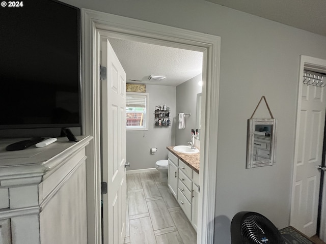 bathroom with a textured ceiling, vanity, and toilet