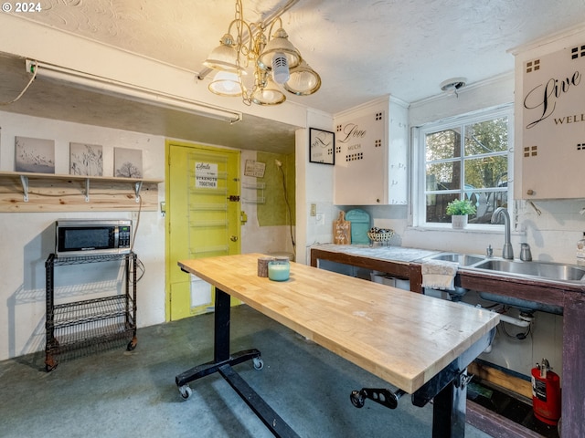 interior space with sink, concrete flooring, pendant lighting, crown molding, and an inviting chandelier