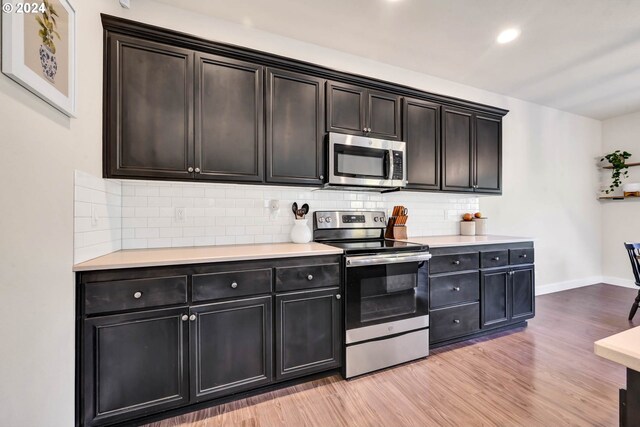 kitchen featuring appliances with stainless steel finishes, light hardwood / wood-style floors, and decorative backsplash