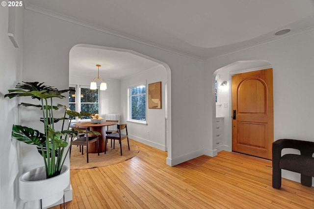 dining room featuring radiator, crown molding, an inviting chandelier, and light wood-type flooring