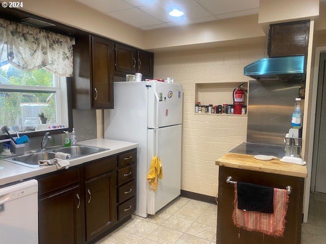 kitchen featuring sink, light tile patterned flooring, white appliances, and dark brown cabinets