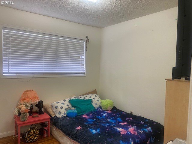 bedroom featuring a textured ceiling and hardwood / wood-style flooring