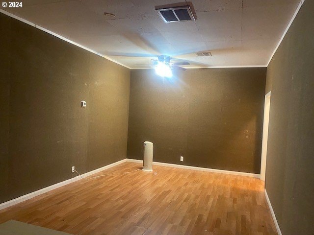 empty room with crown molding and wood-type flooring