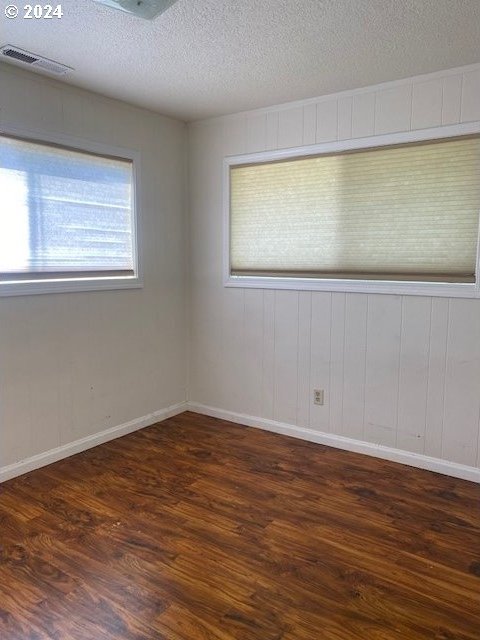 empty room featuring a textured ceiling and hardwood / wood-style floors