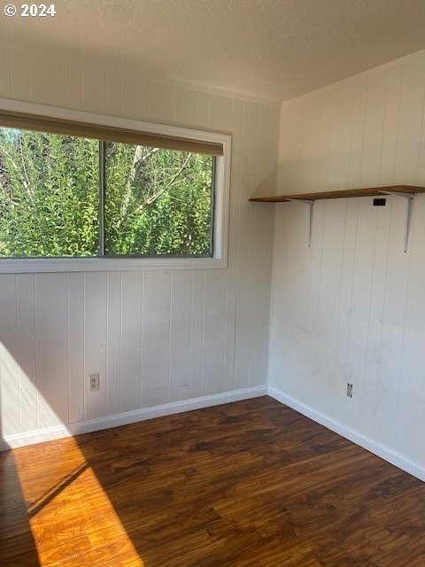 unfurnished room featuring a textured ceiling and dark hardwood / wood-style flooring