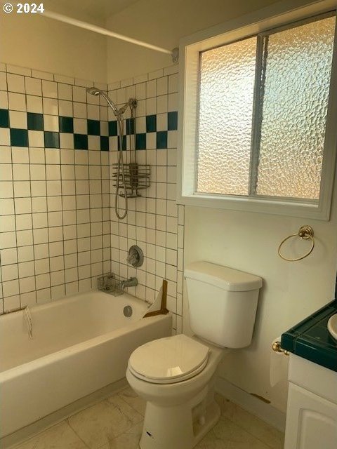 full bathroom featuring toilet, tiled shower / bath, vanity, and tile patterned floors