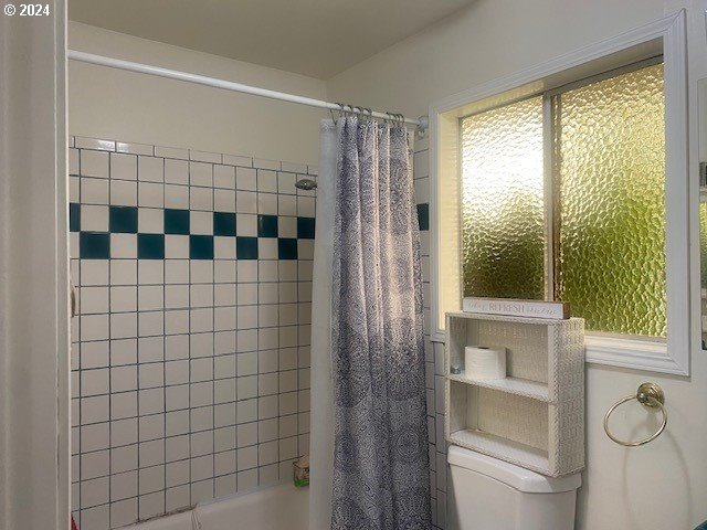 bathroom featuring shower / tub combo and toilet