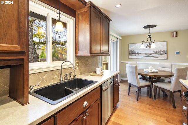 kitchen with hanging light fixtures, sink, stainless steel dishwasher, and plenty of natural light