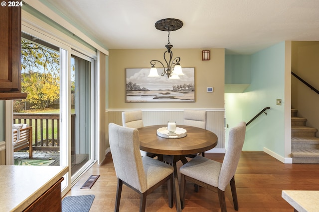 dining space with hardwood / wood-style floors and a notable chandelier