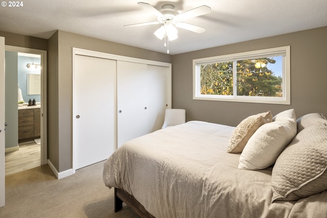 carpeted bedroom with ensuite bath, ceiling fan, a closet, and a textured ceiling