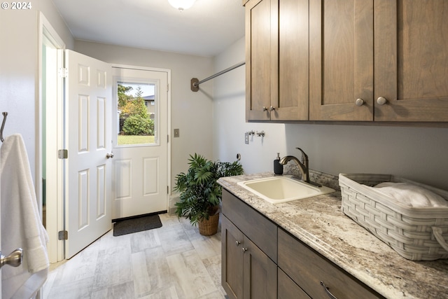 clothes washing area featuring cabinets, light hardwood / wood-style floors, and sink