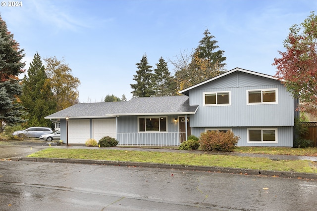 tri-level home featuring a front yard, a porch, and a garage