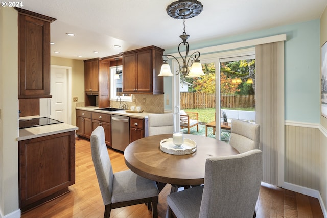 dining area with sink, light hardwood / wood-style floors, and an inviting chandelier