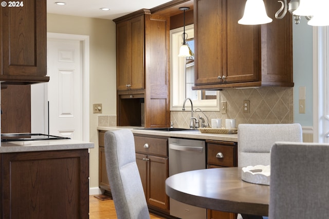 kitchen with decorative backsplash, stainless steel dishwasher, sink, pendant lighting, and light hardwood / wood-style floors