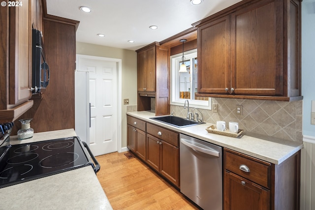 kitchen with electric range oven, stainless steel dishwasher, sink, pendant lighting, and light hardwood / wood-style floors