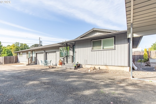 view of front facade with driveway, a garage, and fence