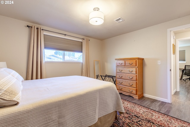 bedroom featuring baseboards, visible vents, and wood finished floors