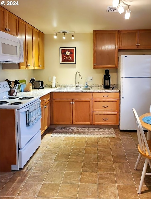 kitchen featuring a sink, light stone counters, brown cabinetry, and white appliances