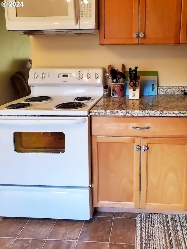 kitchen featuring white appliances and dark tile patterned flooring