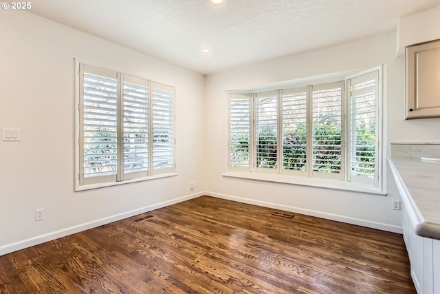 unfurnished room with dark wood-type flooring and a textured ceiling