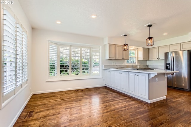 kitchen with stainless steel fridge, a textured ceiling, sink, dark hardwood / wood-style floors, and hanging light fixtures