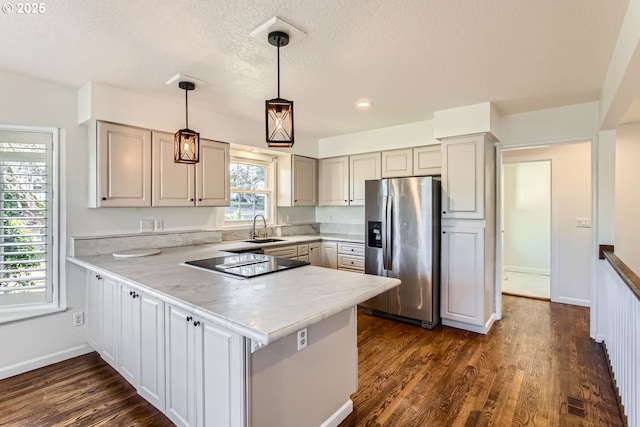 kitchen with kitchen peninsula, black electric cooktop, sink, decorative light fixtures, and stainless steel fridge with ice dispenser