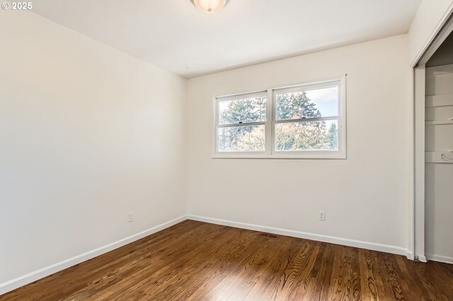 unfurnished bedroom with a closet and dark hardwood / wood-style floors