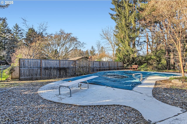 view of swimming pool with a diving board