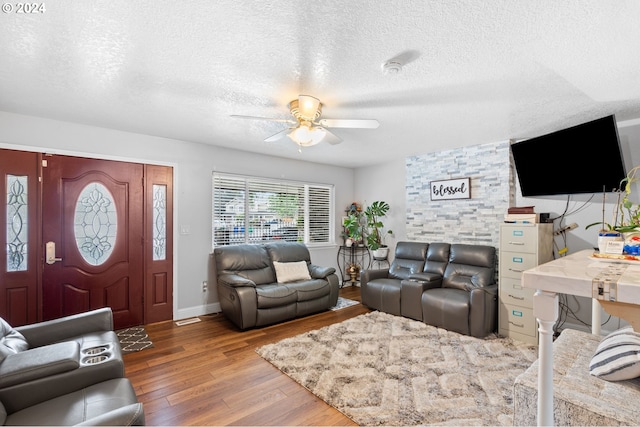 living room featuring wood-type flooring, a textured ceiling, and ceiling fan