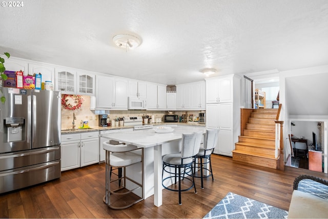 kitchen featuring dark hardwood / wood-style flooring, white cabinets, white appliances, a center island, and light stone counters