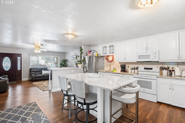 kitchen featuring white appliances, a kitchen island, dark hardwood / wood-style flooring, white cabinetry, and ceiling fan