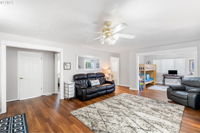 living room featuring dark wood-type flooring, a textured ceiling, and ceiling fan