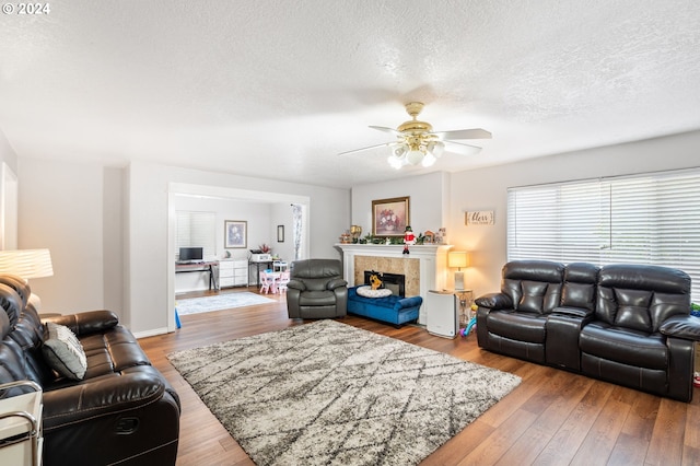 living room featuring a fireplace, a textured ceiling, ceiling fan, and hardwood / wood-style floors