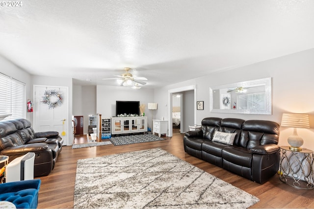 living room with a textured ceiling, hardwood / wood-style floors, and ceiling fan