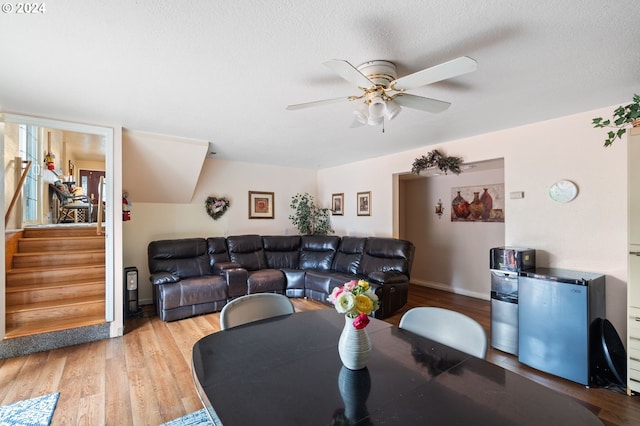 living room with light hardwood / wood-style flooring, a textured ceiling, and ceiling fan