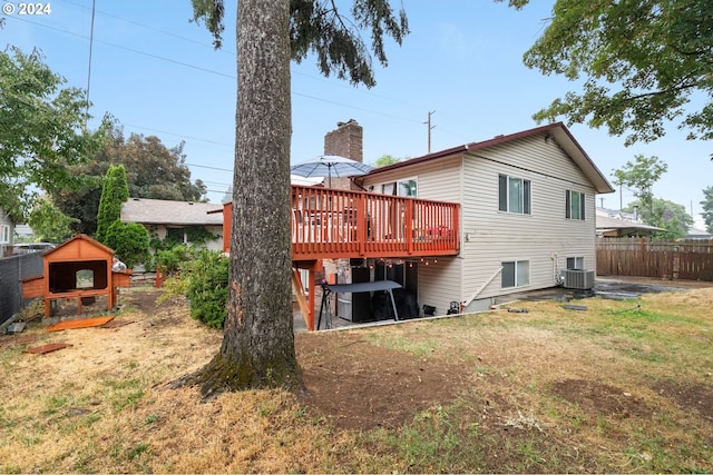 rear view of house with cooling unit, a wooden deck, a shed, and a lawn