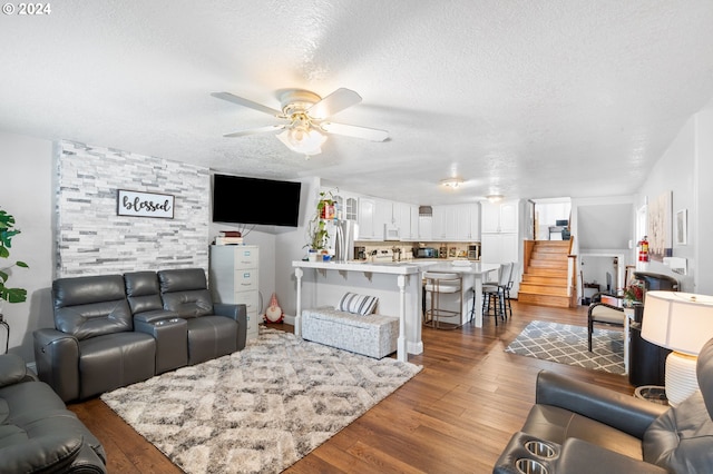 living room featuring ceiling fan, hardwood / wood-style flooring, and a textured ceiling