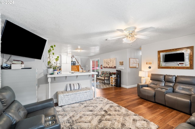 living room with a textured ceiling, ceiling fan, and hardwood / wood-style floors