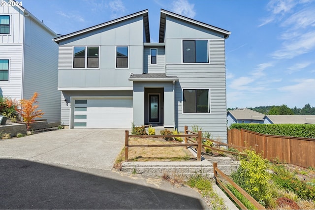 contemporary house with driveway, a garage, fence, and board and batten siding