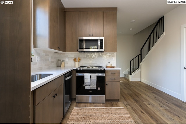 kitchen with hardwood / wood-style flooring, appliances with stainless steel finishes, and backsplash