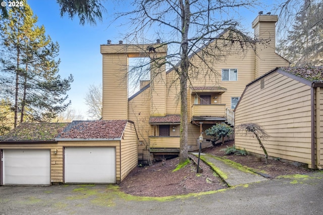 rear view of house featuring a balcony and a garage