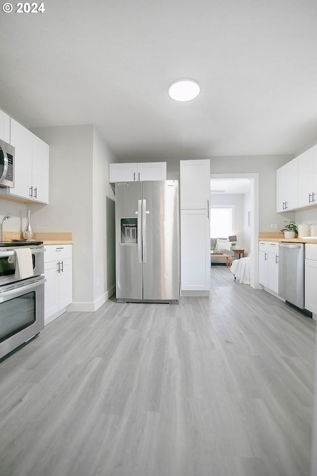 kitchen with appliances with stainless steel finishes, light countertops, and white cabinetry