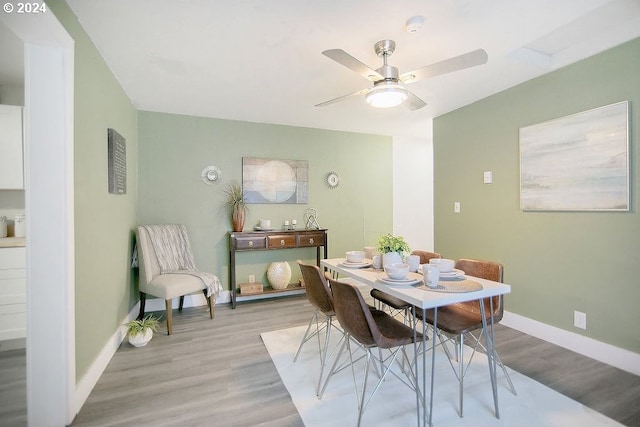 dining area with a ceiling fan, baseboards, and light wood finished floors