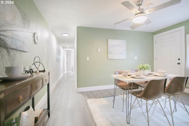 dining area featuring light wood-type flooring, baseboards, and a ceiling fan