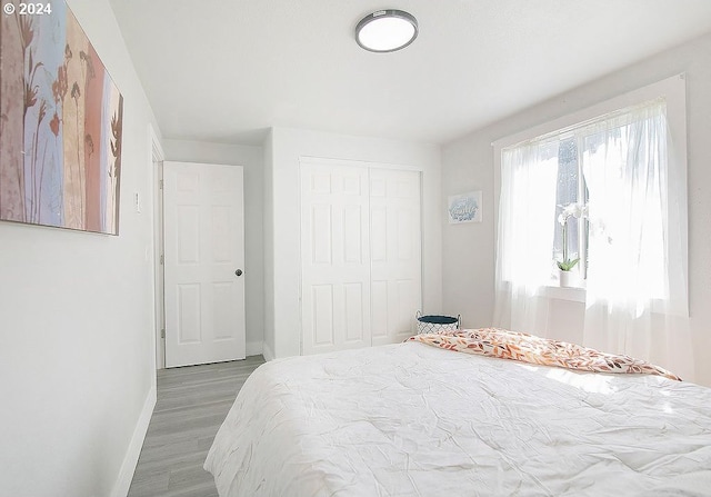 bedroom with baseboards, a closet, and wood finished floors