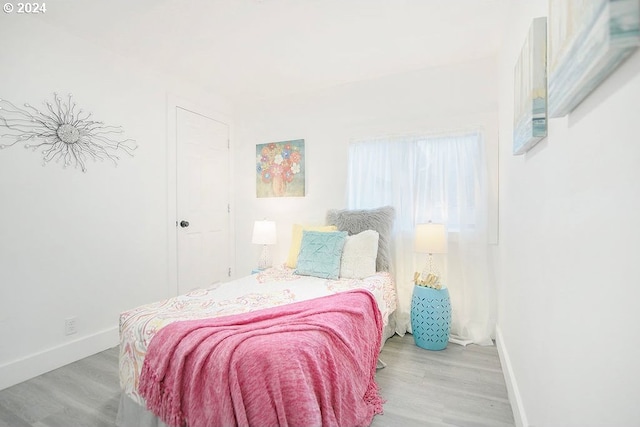 bedroom with light wood finished floors and baseboards