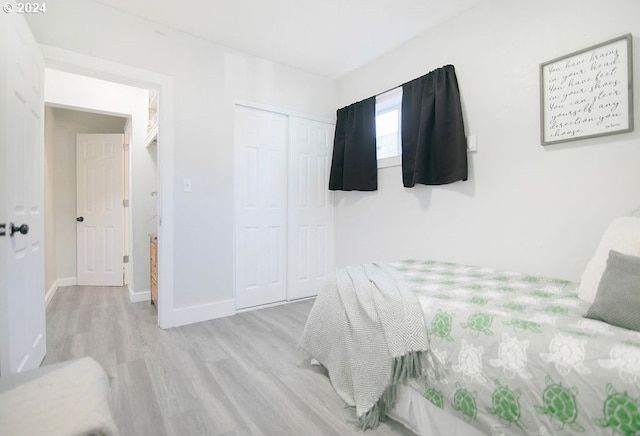 bedroom featuring a closet, light wood-style flooring, and baseboards