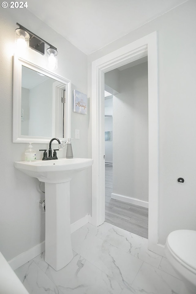 half bathroom featuring marble finish floor, toilet, and baseboards